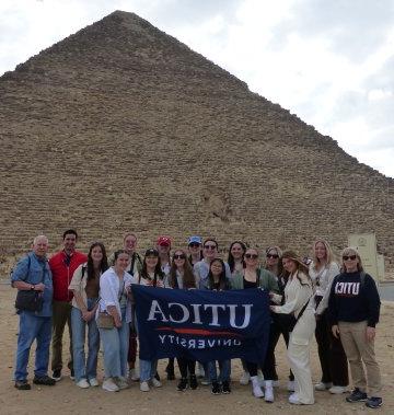 Students and 教师 hold up a 利记sbo banner at the Great Pyramid during a January 2023 visit to 埃及.