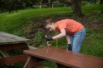 A new Utica student paints a picnic table at the 2023 Pioneer Pitch In.