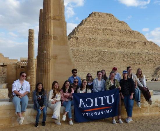 Students hold up a Utica University banner at Saqqara during a January 2023 trip to Egypt.